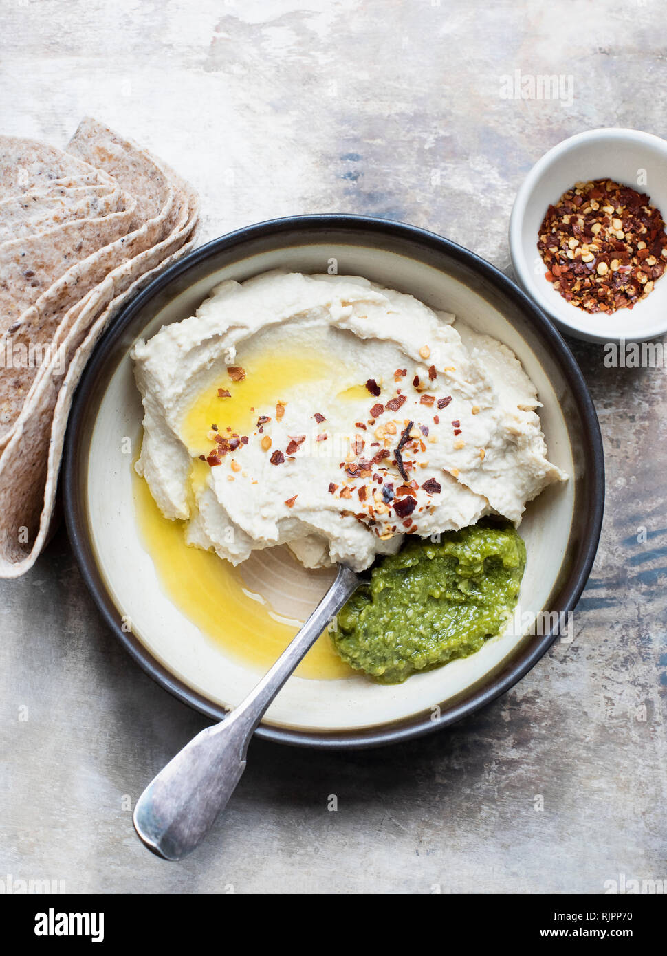 Pita bread with hummus and basil pesto dip, chilli flakes Stock Photo