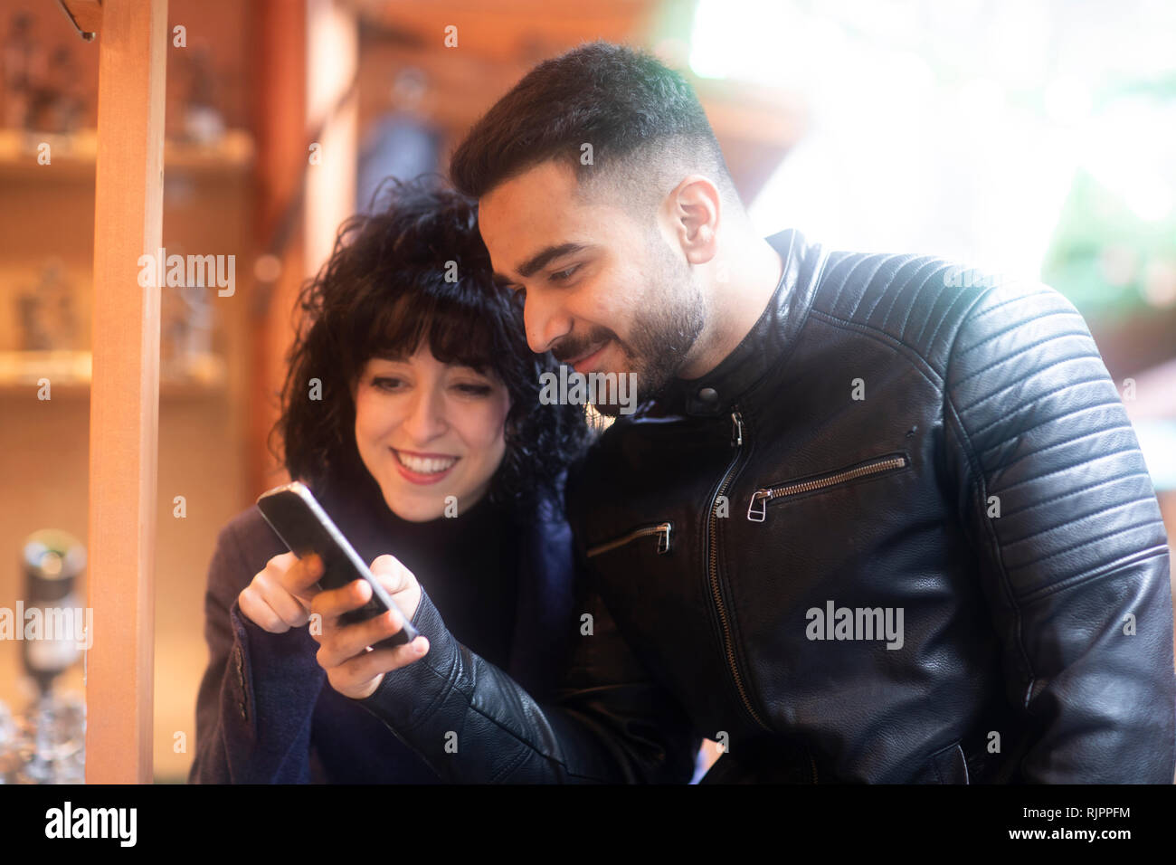 Couple using smartphone at Christmas market, Freiburg, Baden-Wurttemberg, Germany Stock Photo