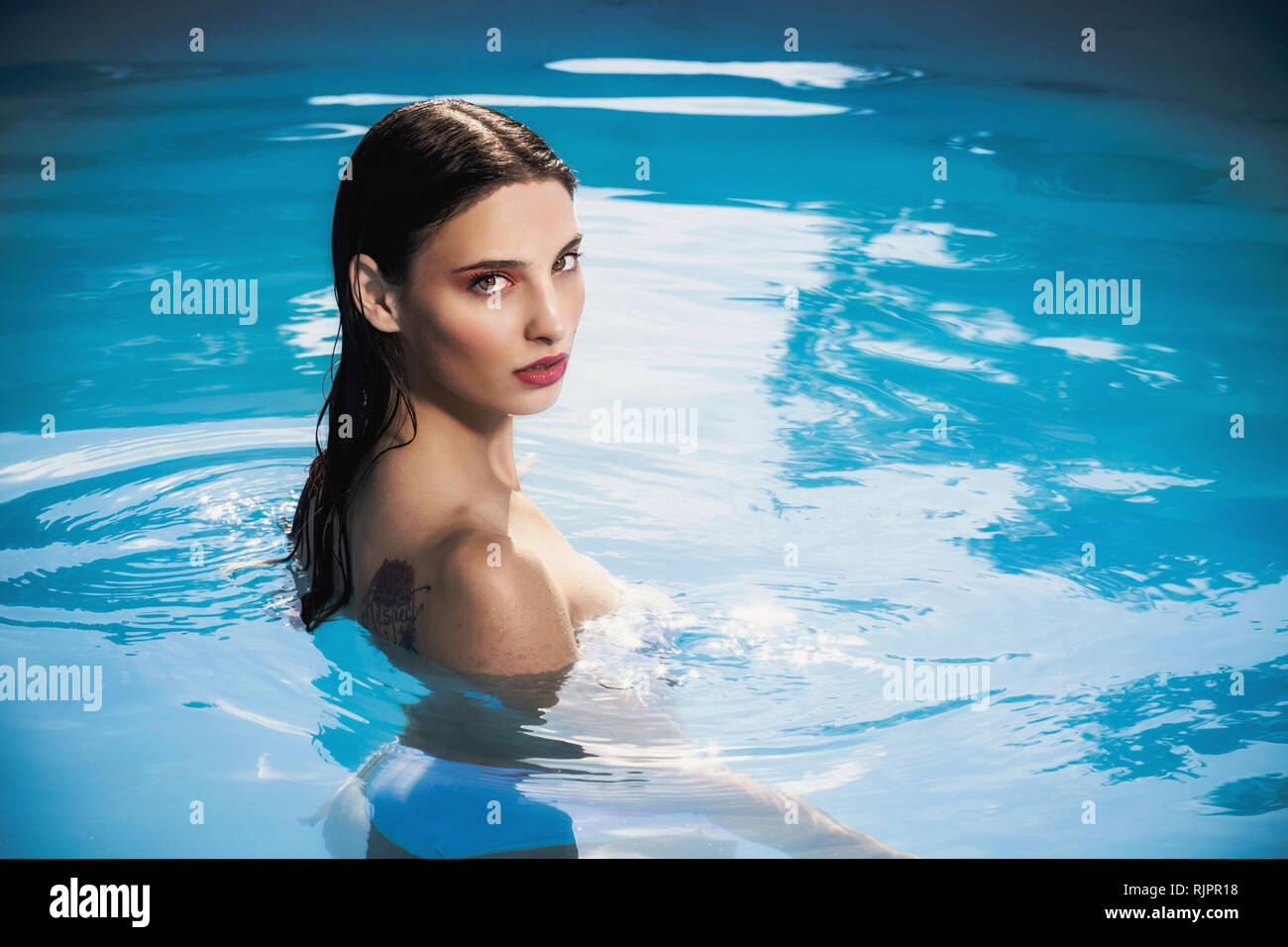 Sultry young woman standing in outdoor swimming pool, portrait, Cagliari, Sardinia, Italy Stock Photo