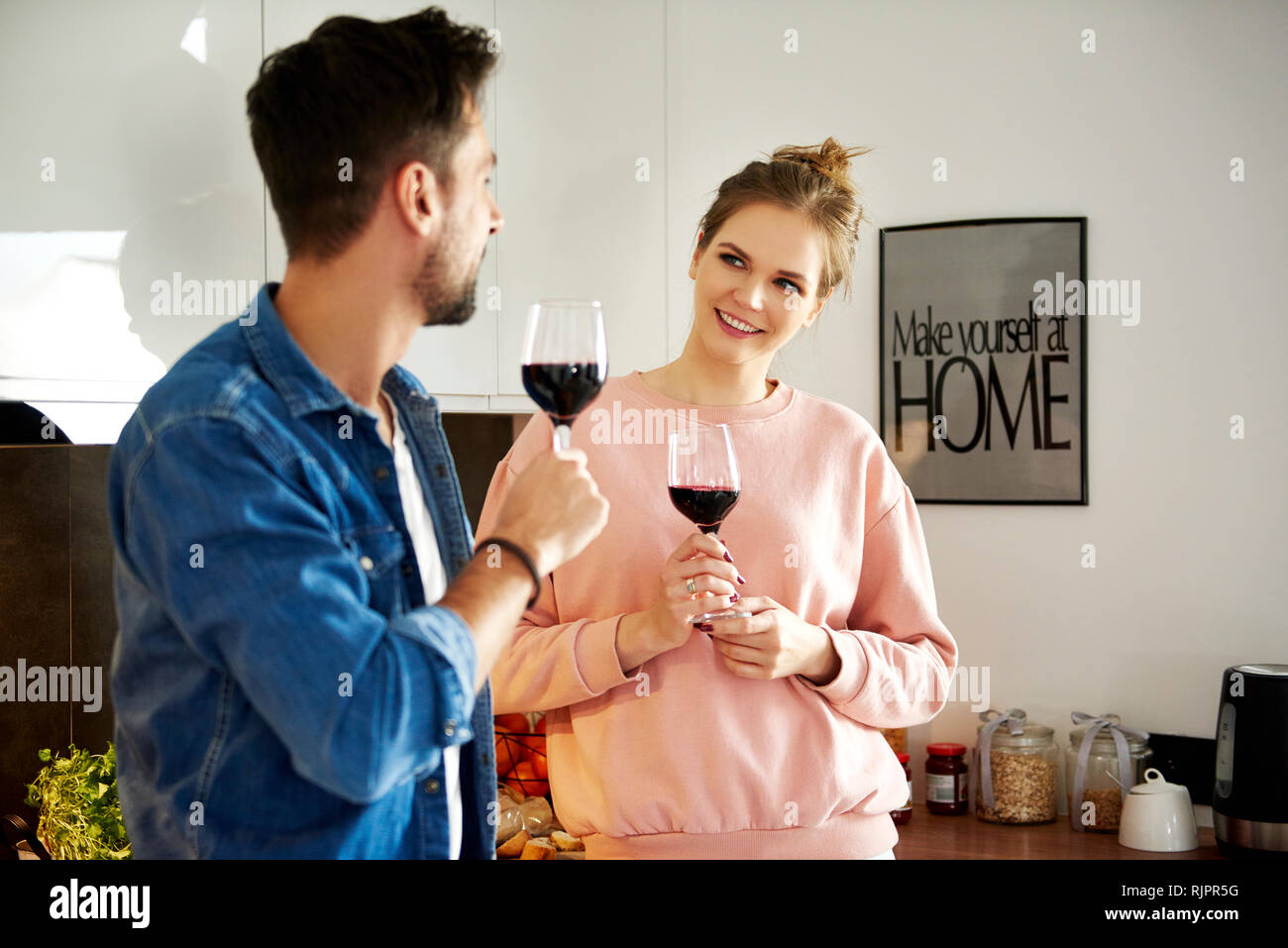 Couple talking and drinking red wine in kitchen Stock Photo Alamy