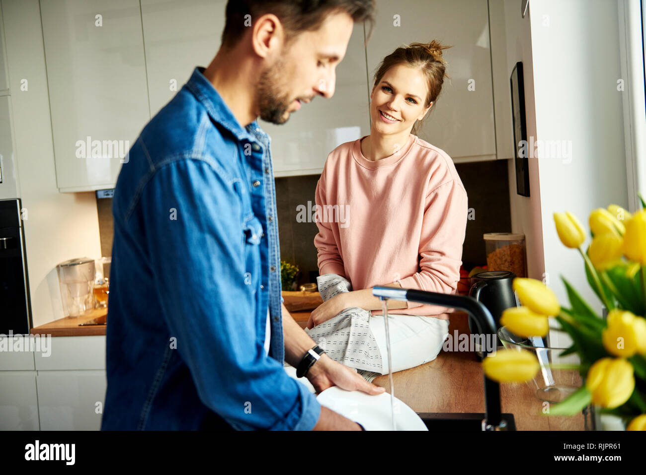 Couple talking and washing up in kitchen Stock Photo