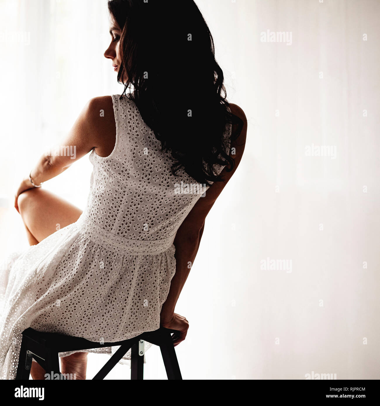 Woman in summer dress on bar stool Stock Photo