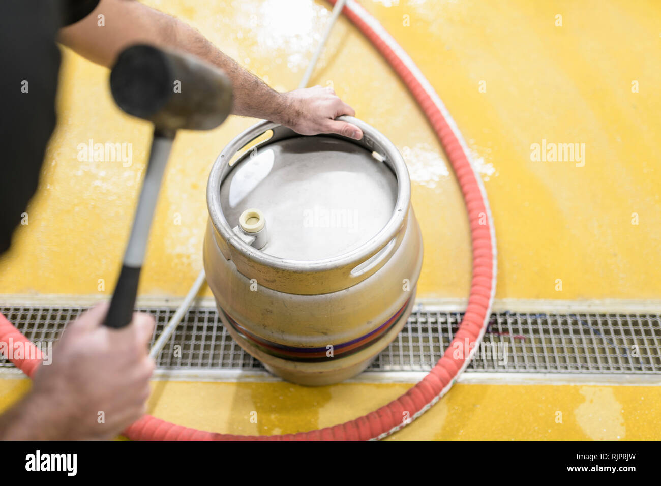 Worker hammering plug into beer barrel in small brewery Stock Photo