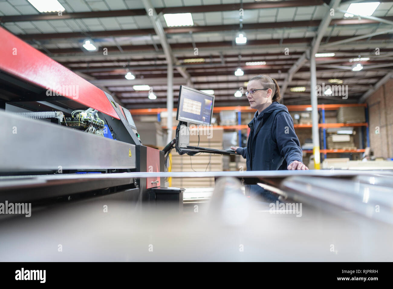 Female printing machine operator in cardboard box factory Stock Photo