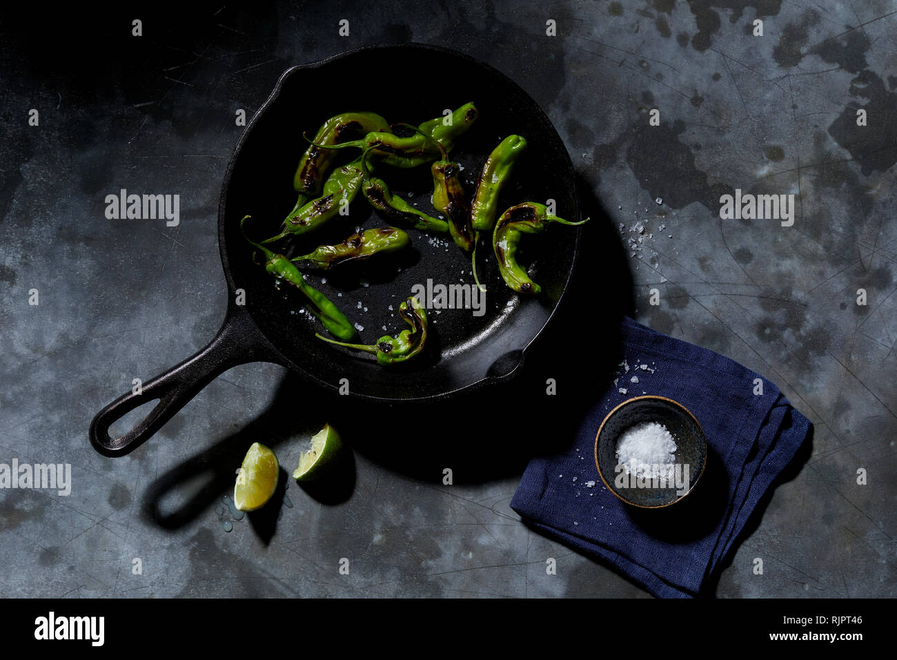 Skillet with saute shishito peppers with lime and sea salt, overhead view Stock Photo