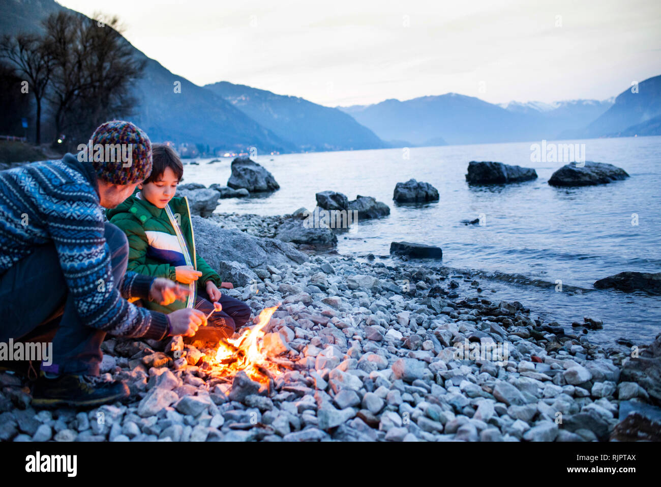 Father and son toasting marshmallows over campfire, Onno, Lombardy, Italy Stock Photo