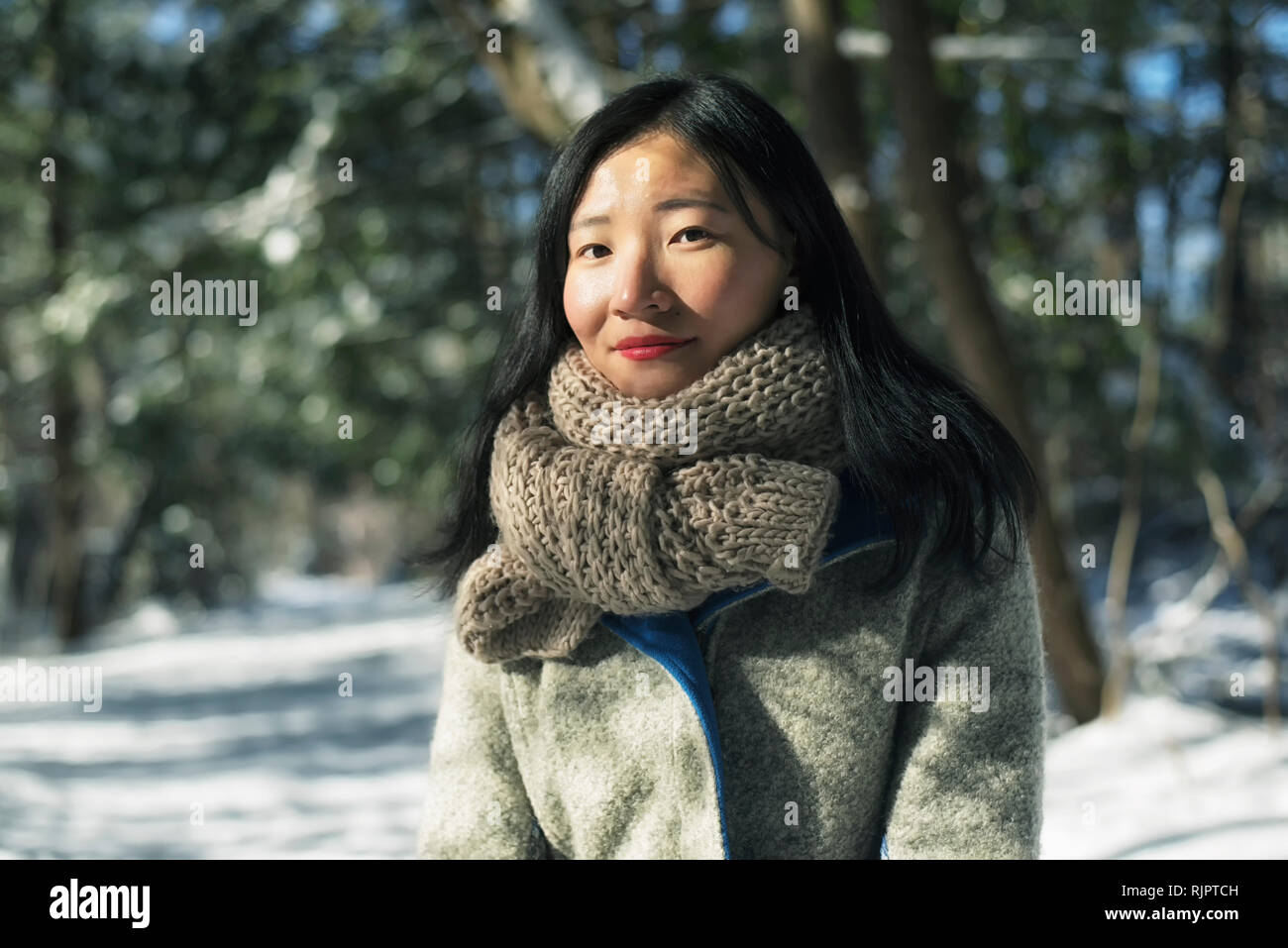 A chinese woman looking at the camera outside in a wintery scene at white memorial conservation area in Litchfield Connecticut, new england. Stock Photo