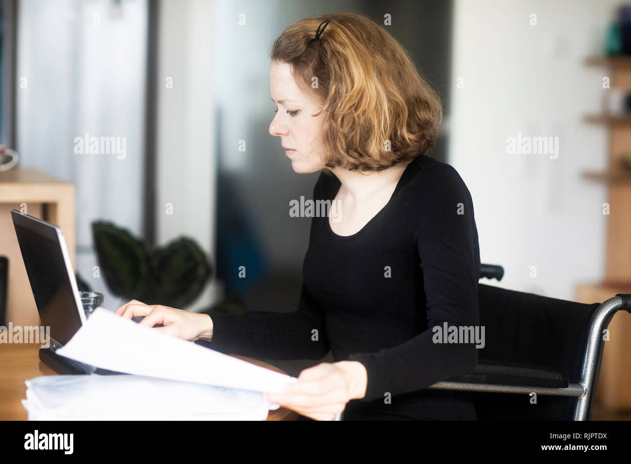 Woman in wheelchair working at laptop Stock Photo