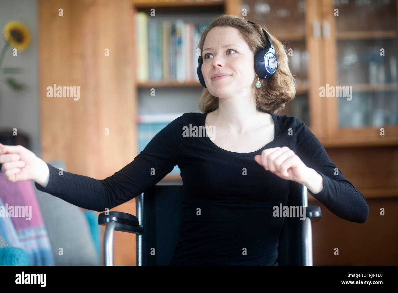 Woman in wheelchair dancing to music on headphones Stock Photo
