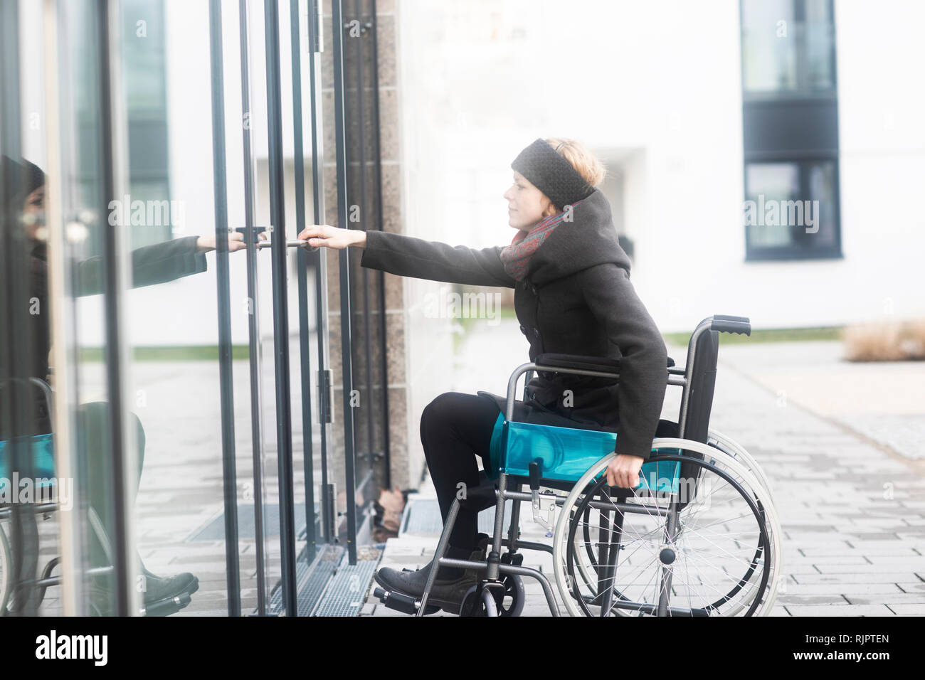 Woman in wheelchair opening door to building Stock Photo Alamy