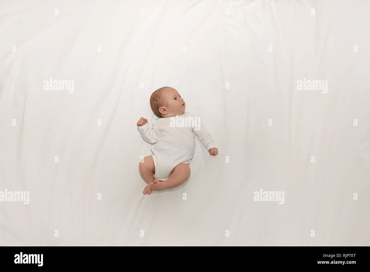 Tiny baby on spacious bed Stock Photo