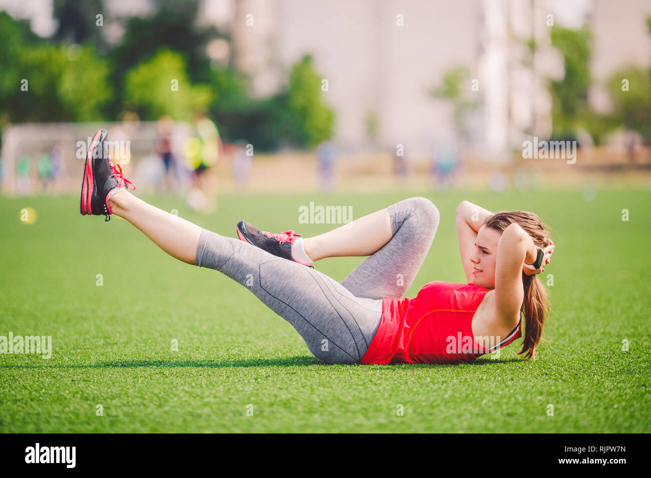 Theme sport and health. Young beautiful Caucasian woman doing warm-up, warming up muscles, abdominal muscles workout, losing belly, abdominal green Stock Photo
