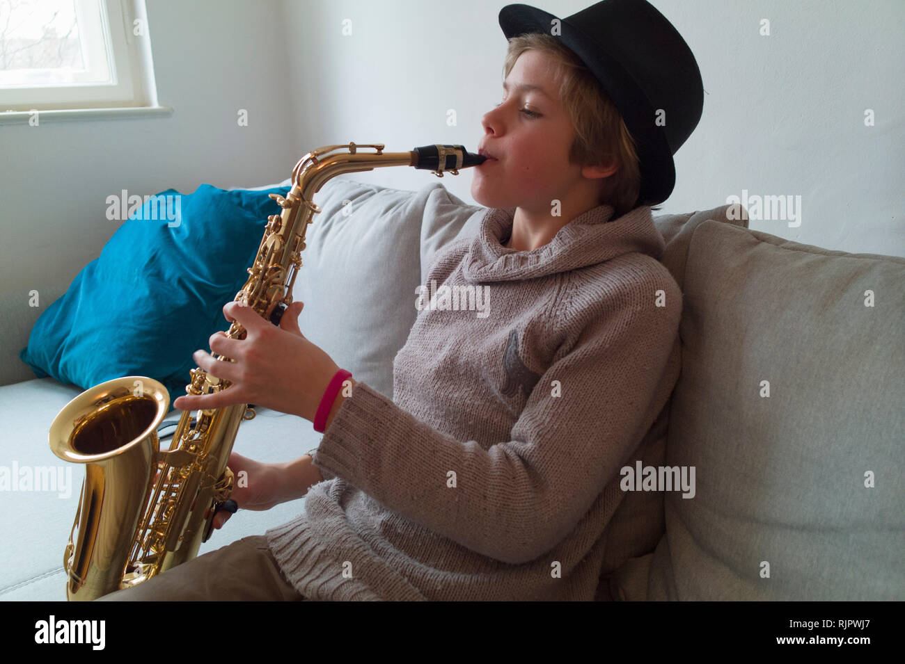 Boy practising saxophone on sofa Stock Photo
