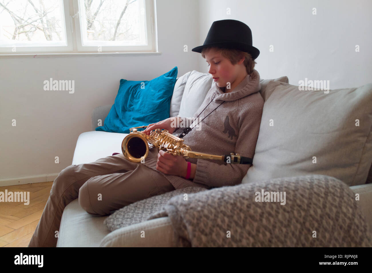 Boy practising saxophone on sofa Stock Photo