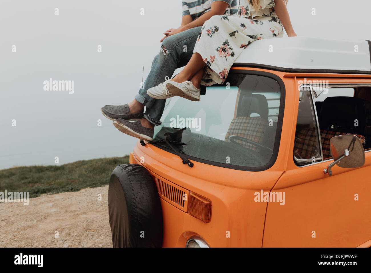 Young couple on top of recreational vehicle at coastal roadside, cropped, Jalama, California, USA Stock Photo