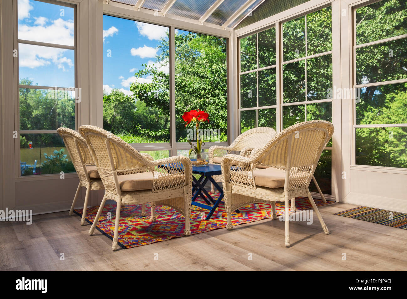 Beige wicker armchairs and blue wooden table in sunroom Stock Photo