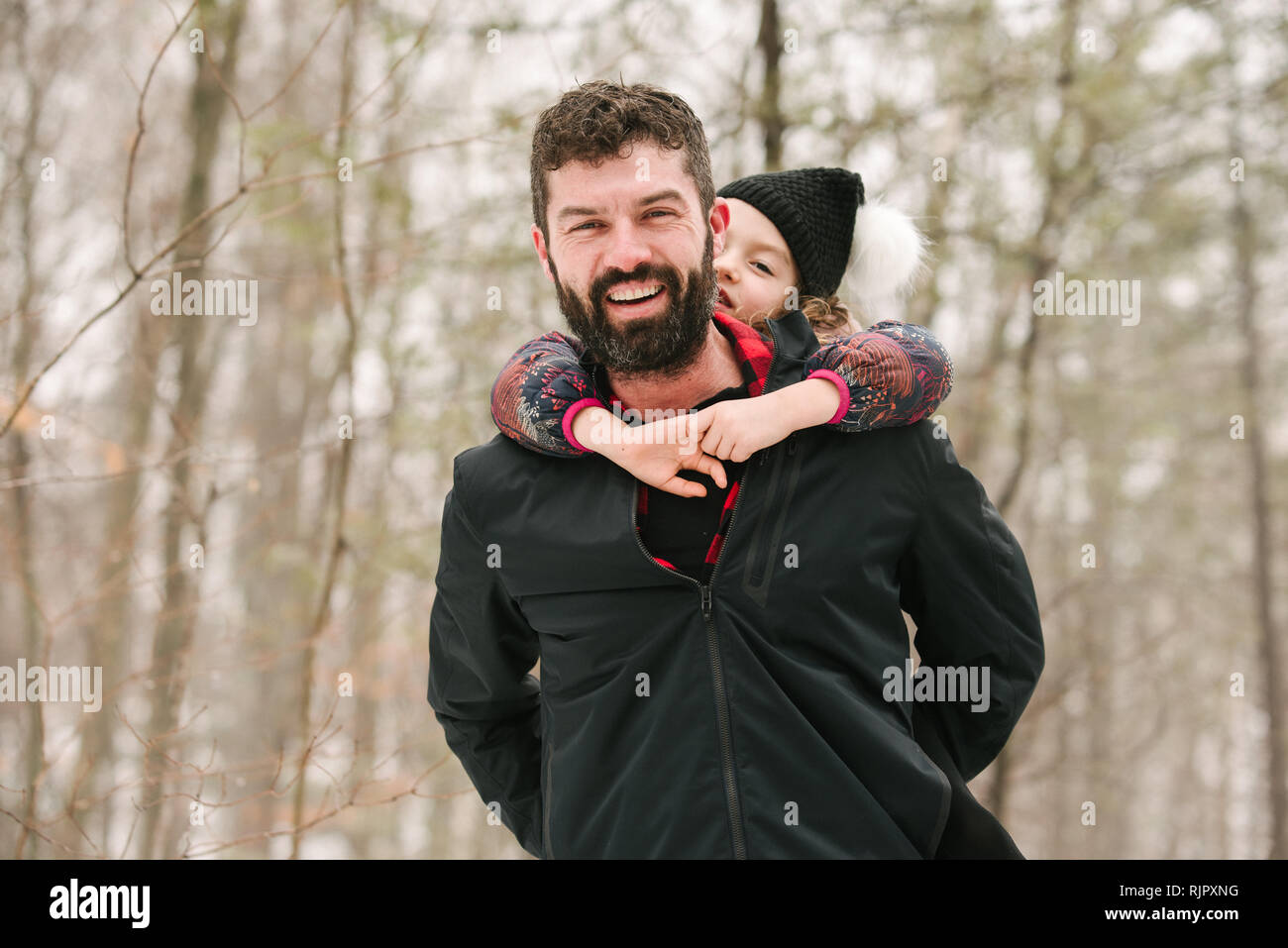 Father piggybacking daughter in forest Stock Photo