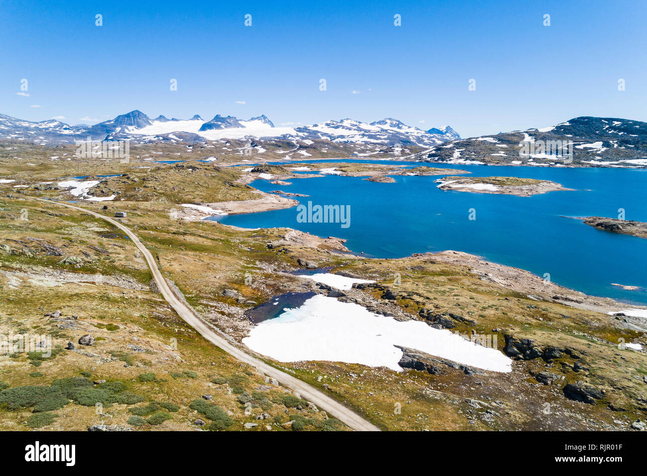 Snow covering part of landscape by lake and mountains, drone view, Sognefjell, Jotunheimen, Norway, Europe Stock Photo