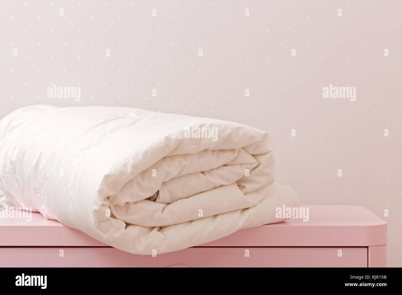 A rolled up duvet is lying on the dresser. Blanket for a bed Stock