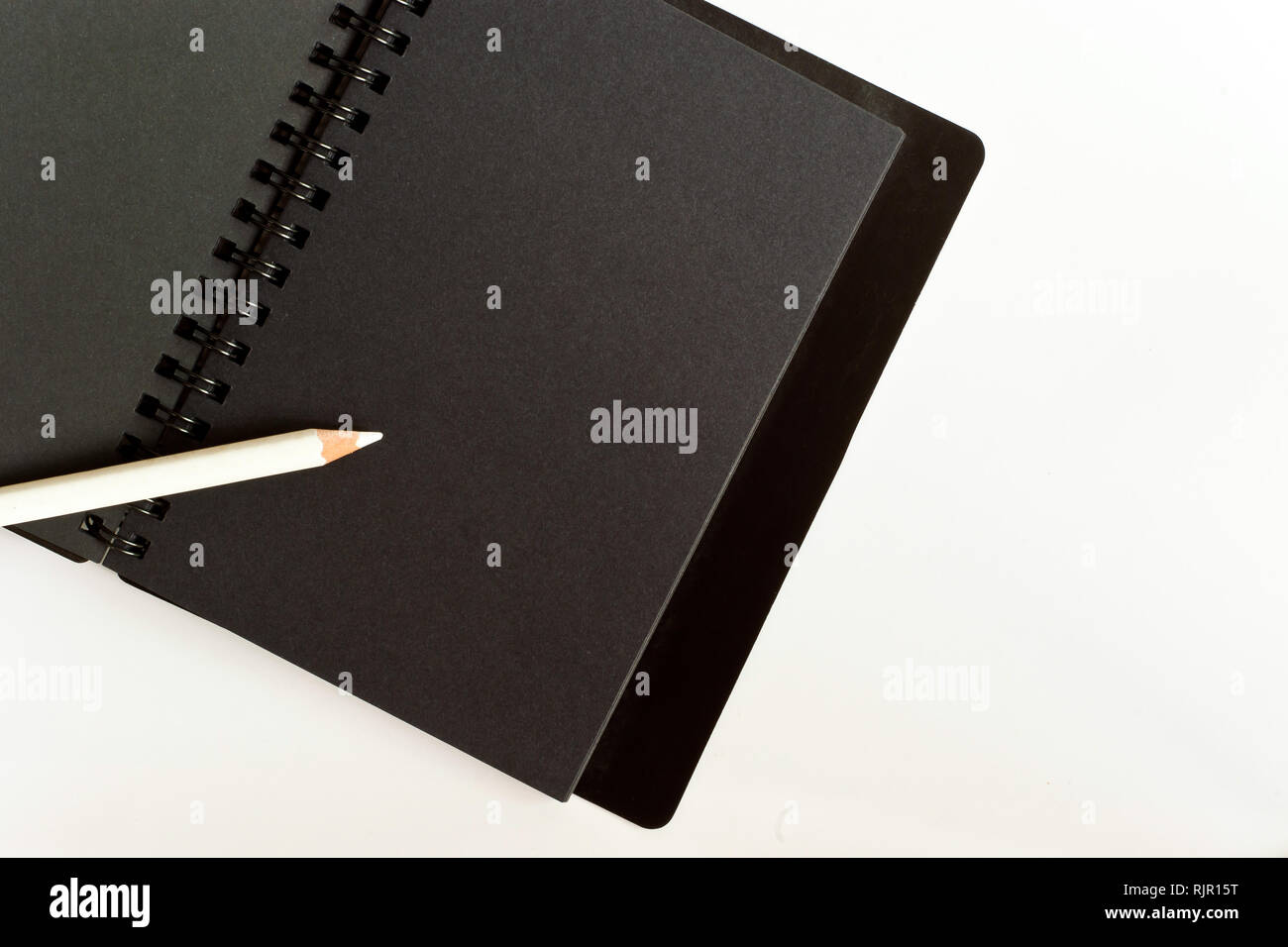 Black paper spiral notebook and white pencil Stock Photo Alamy