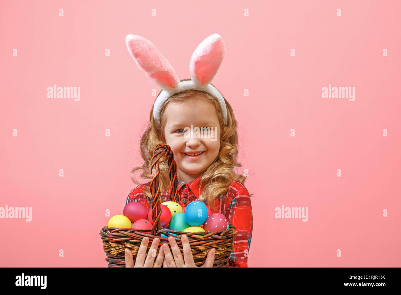 Cute little child girl with bunny ears holding basket of Easter eggs on ...