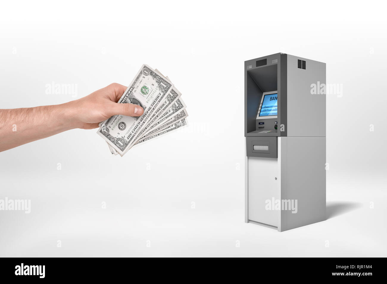 Man's hand holding dollar banknotes and reaching out for an ATM on a white background. Planning budget. Loading account. Cash deposit. Stock Photo
