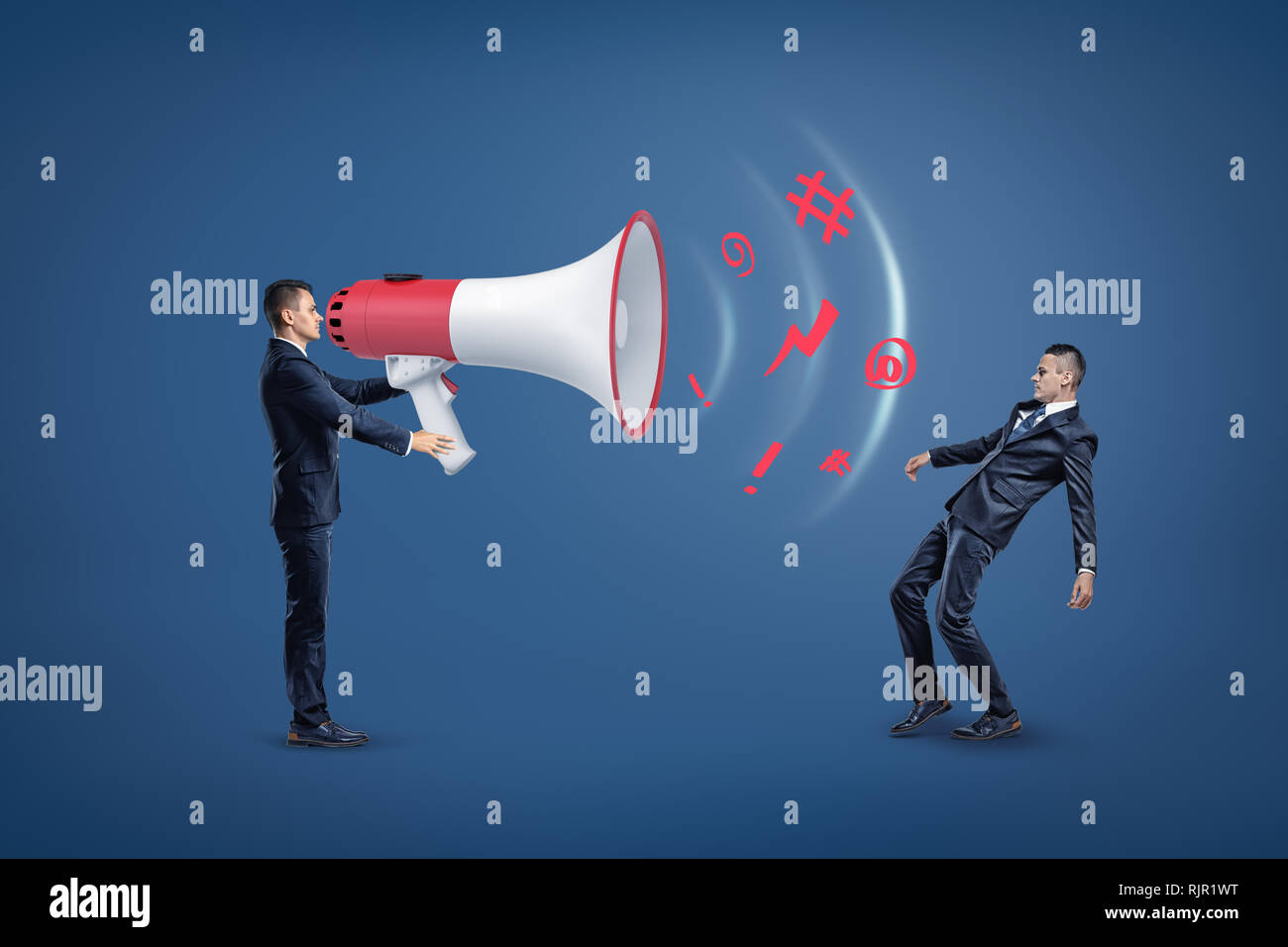 Businessman with huge loud-speaker uttering a message encoded in keyboard symbols, with a sound wave that is knocking the other man off his feet. Word Stock Photo