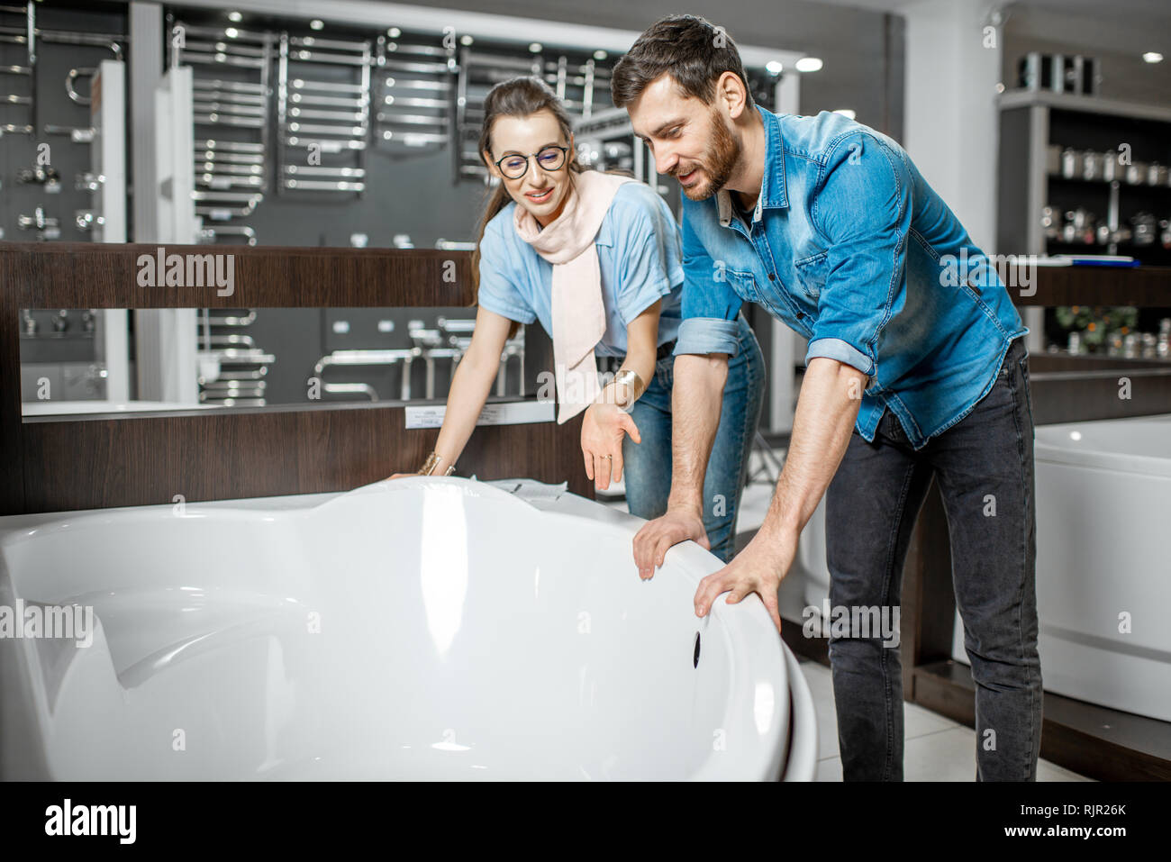 Man and woman choosing new bathtube standing together in the plumbing shop Stock Photo