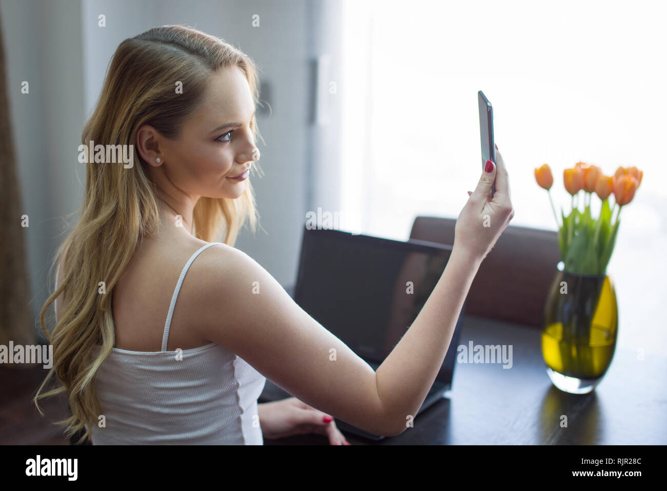 Young blonde woman video calling on smartphone at home Stock Photo