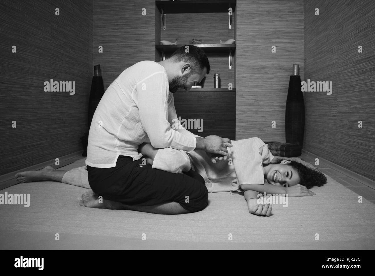 Tibetan massage. The massage therapist makes a Tibetan massage to a young woman. man and woman in white doing gymnastics Stock Photo