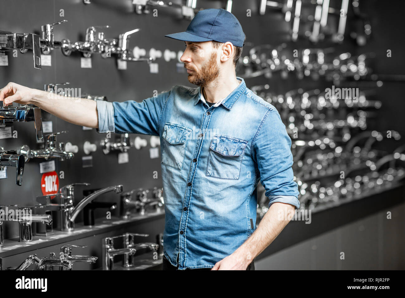 Handsome repairman or worker choosing sanitary taps standing near the