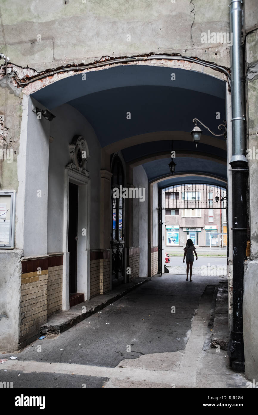 women in silhouette in an arched alleyway with crumbling old building Stock Photo