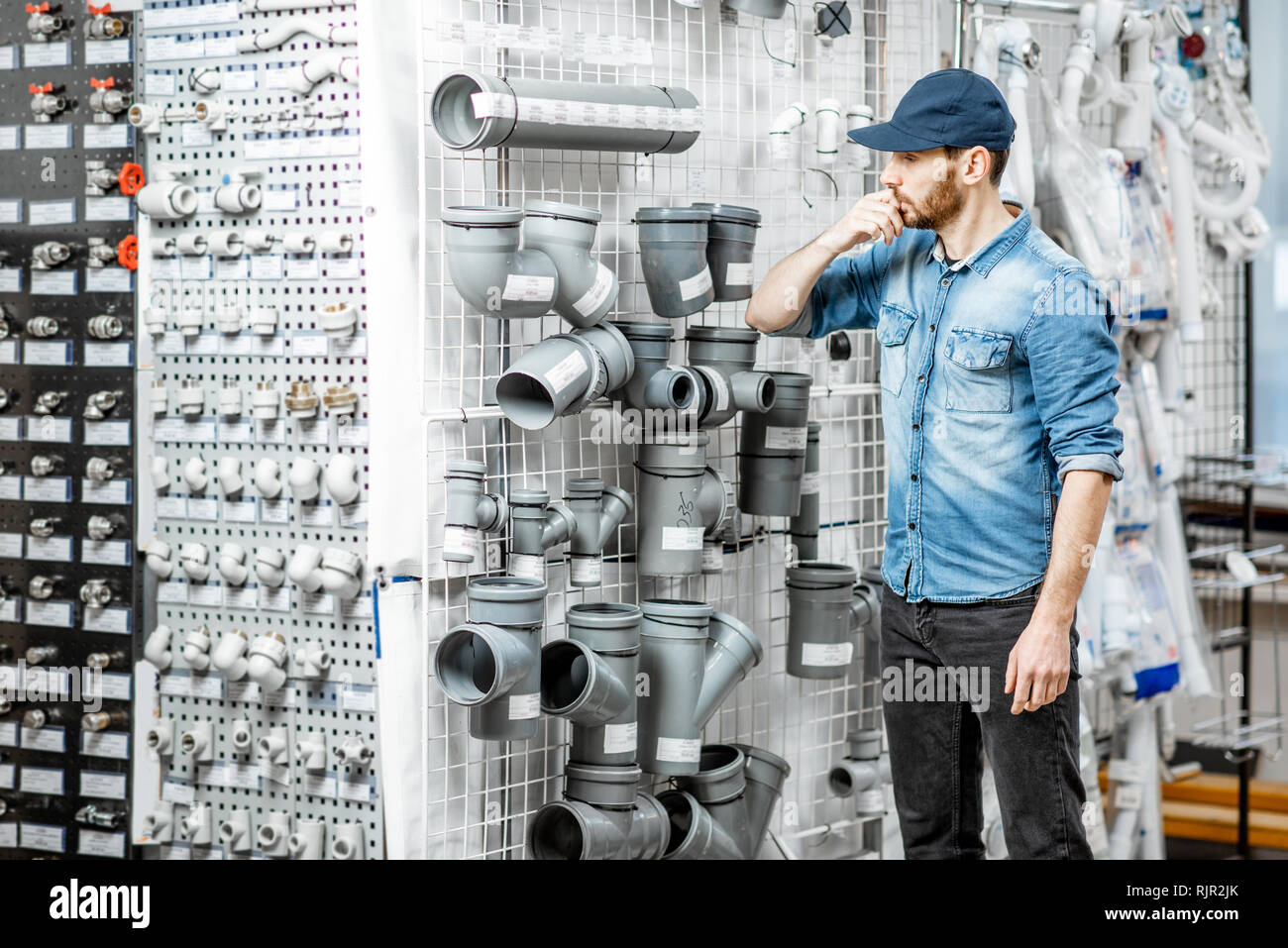 Handsome workman choosing sewer pipes standing near the showcase of the