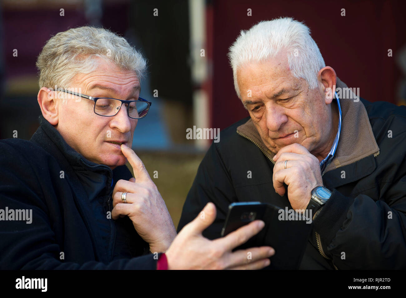 Italy, Lombardy, Monza, the elderly on the bench study how a mobile phone works Stock Photo