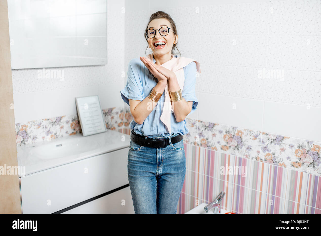 Portrait of a happy woman with excited emotions in the bathroom corner of the shop with ceramic tiles and sanitary goods Stock Photo
