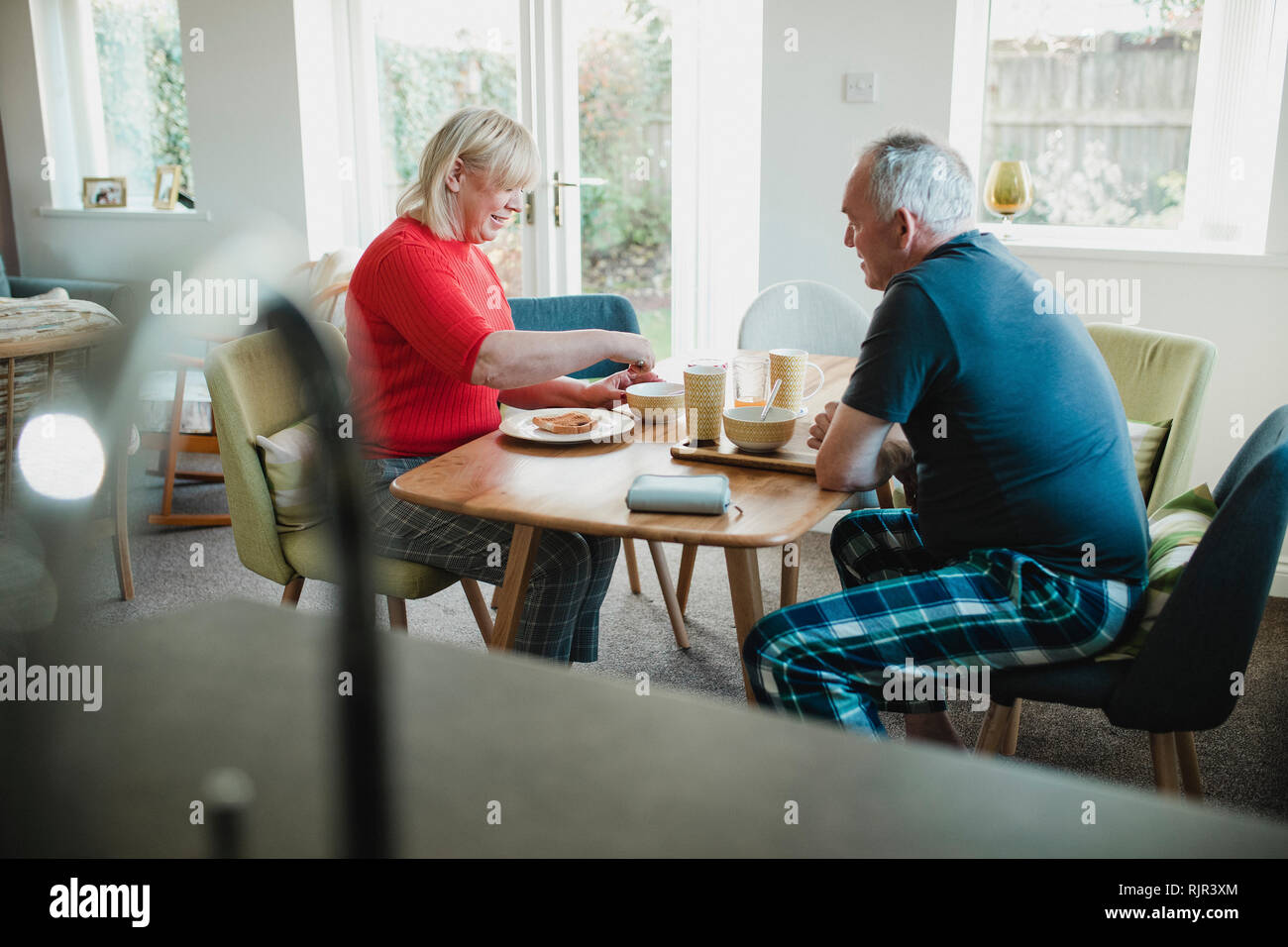 Mature couple are having breakfast together at the dining table in their home. Stock Photo