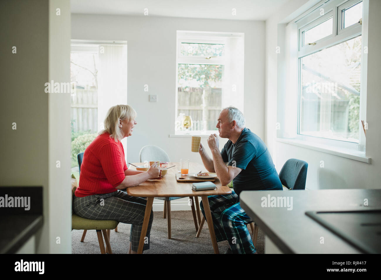 Mature couple are having breakfast together at the dining table in their home. Stock Photo
