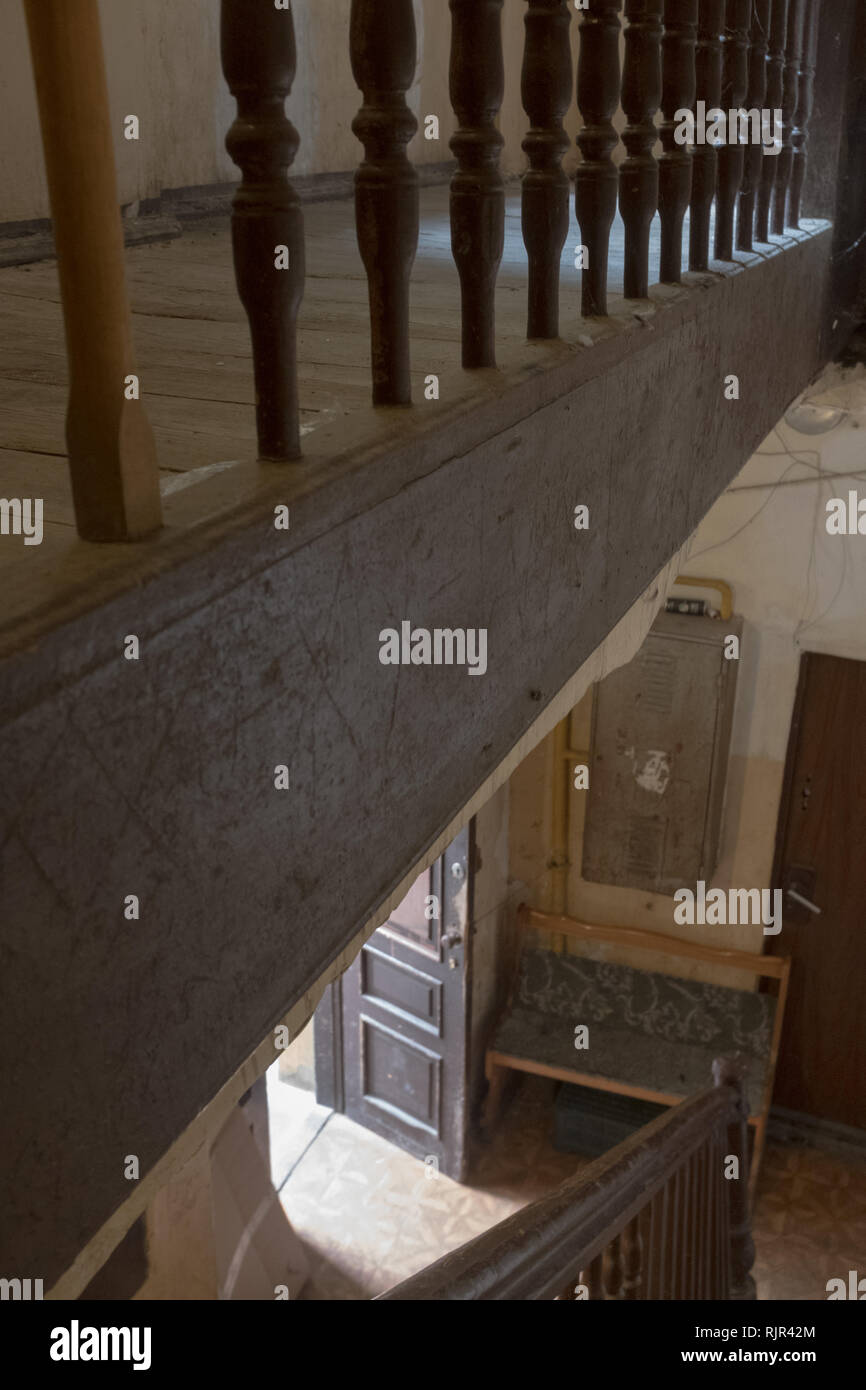 a view from the top of the stairs of a front door and and a hallway with a bench. Stock Photo