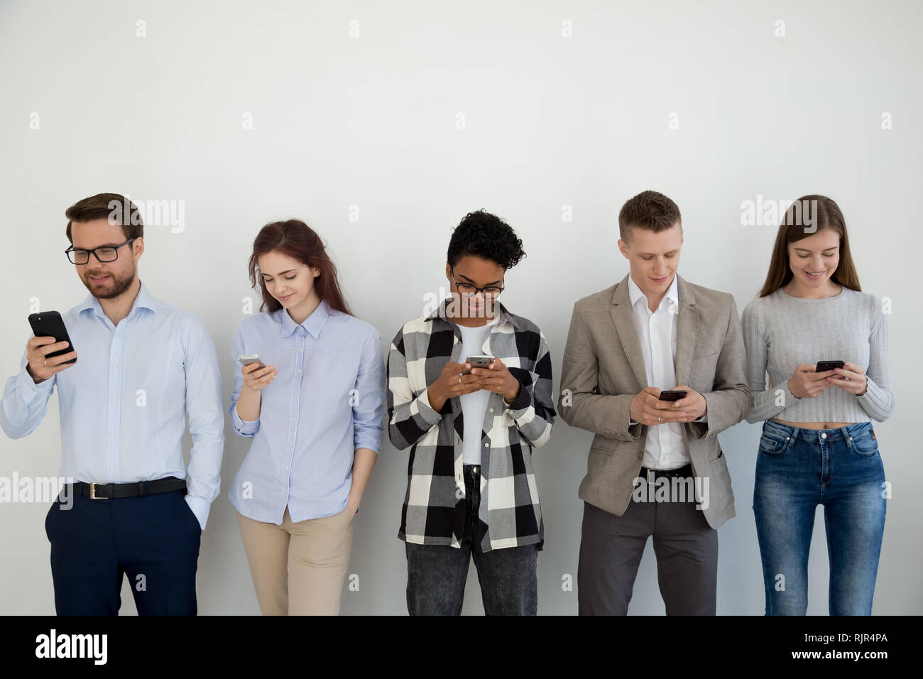 Millennial phone users businesspeople group standing in row using smartphones Stock Photo