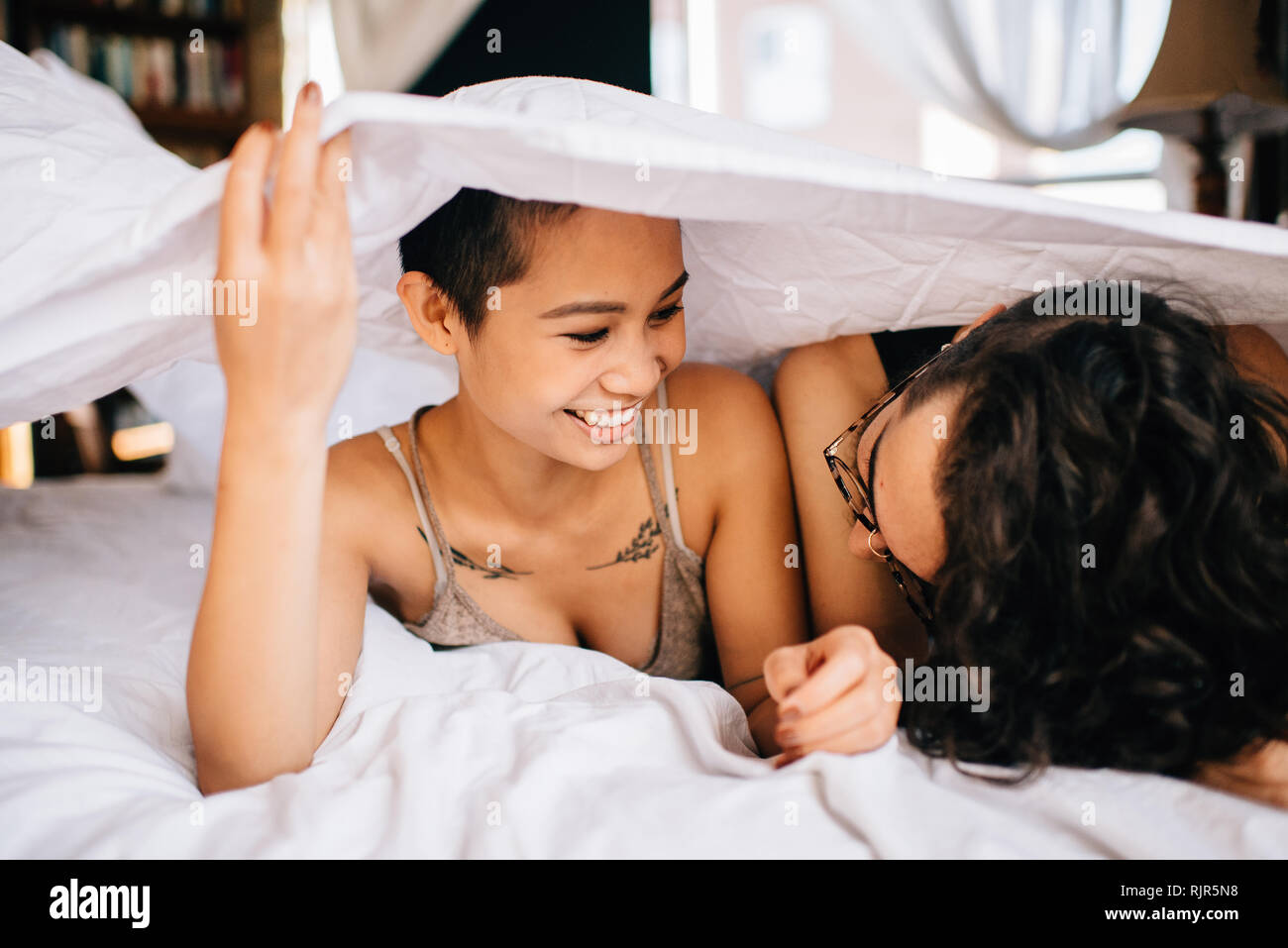 Happy couple under covers in bed Stock Photo