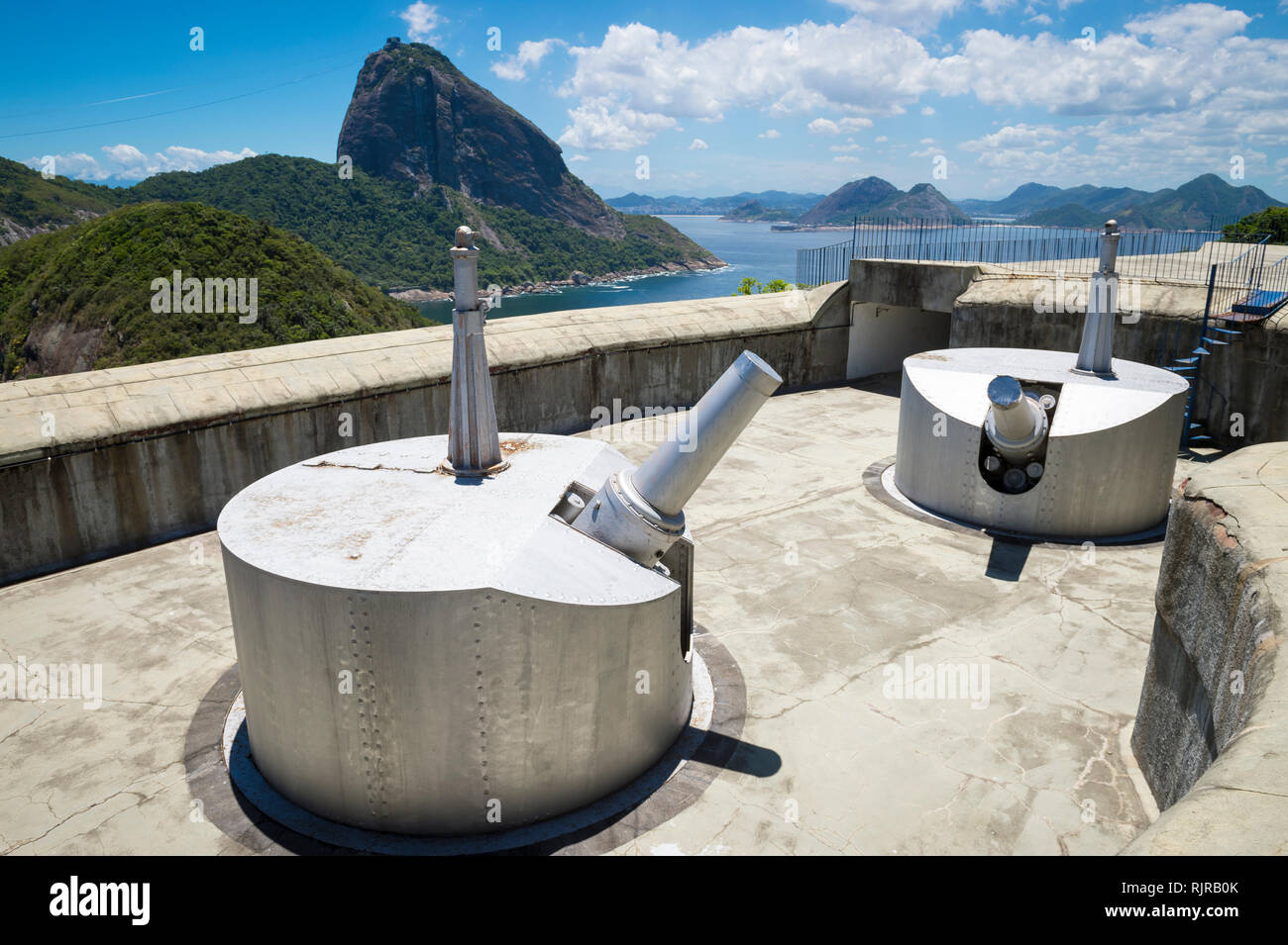 Bright scenic overlook of Sugarloaf Mountain and the Bahia de Guanabara  with decommissioned artillery guns in the foreground in Rio de Janeiro Brazil Stock Photo