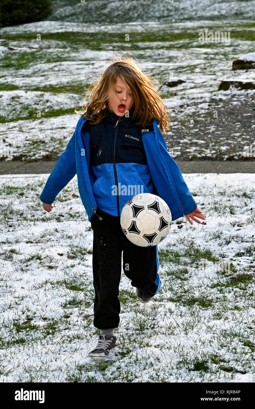 Young long haired boy playing with soccer ball Stock Photo