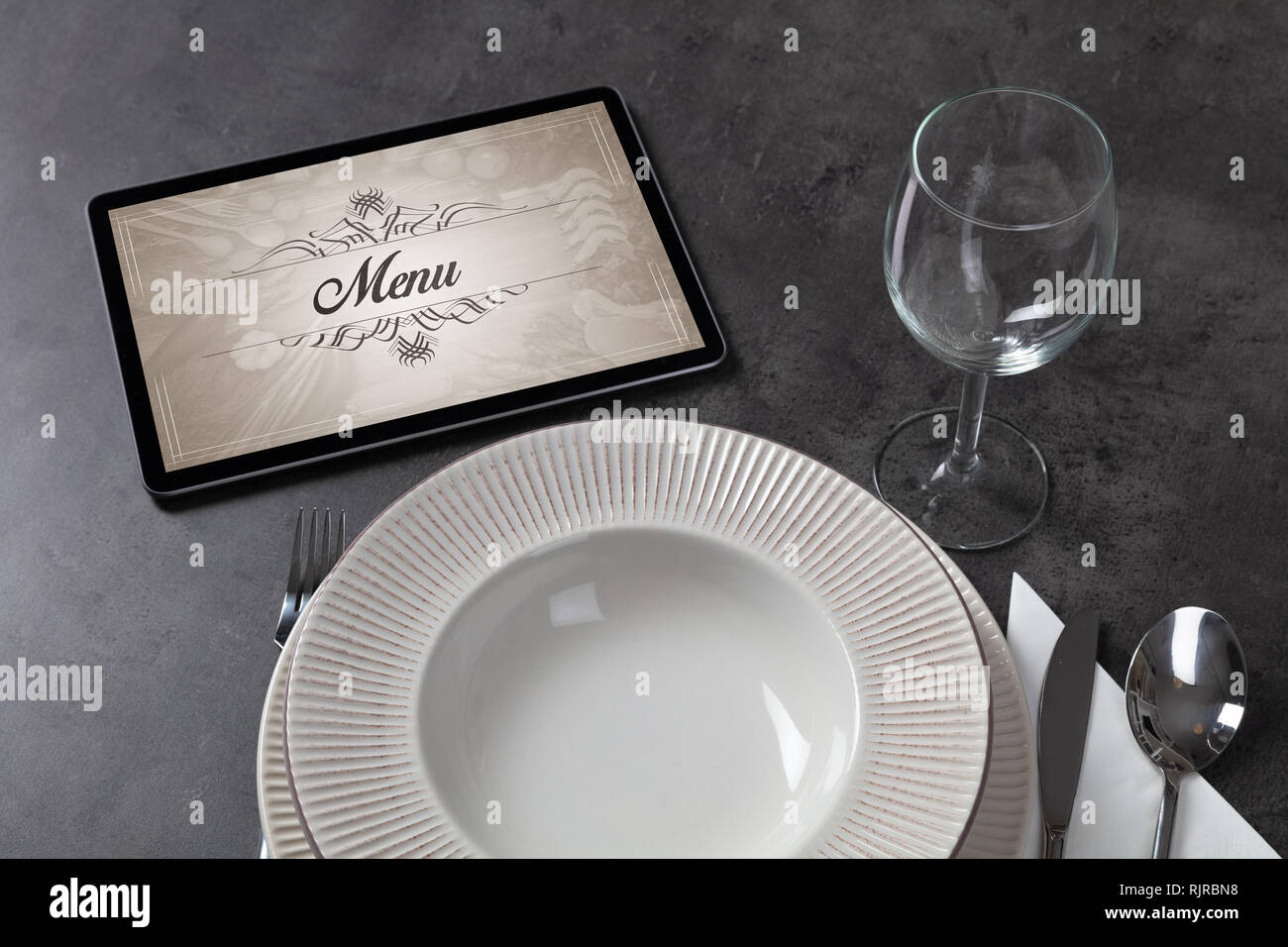Tablet with stylish restaurant logo and laid table  Stock Photo