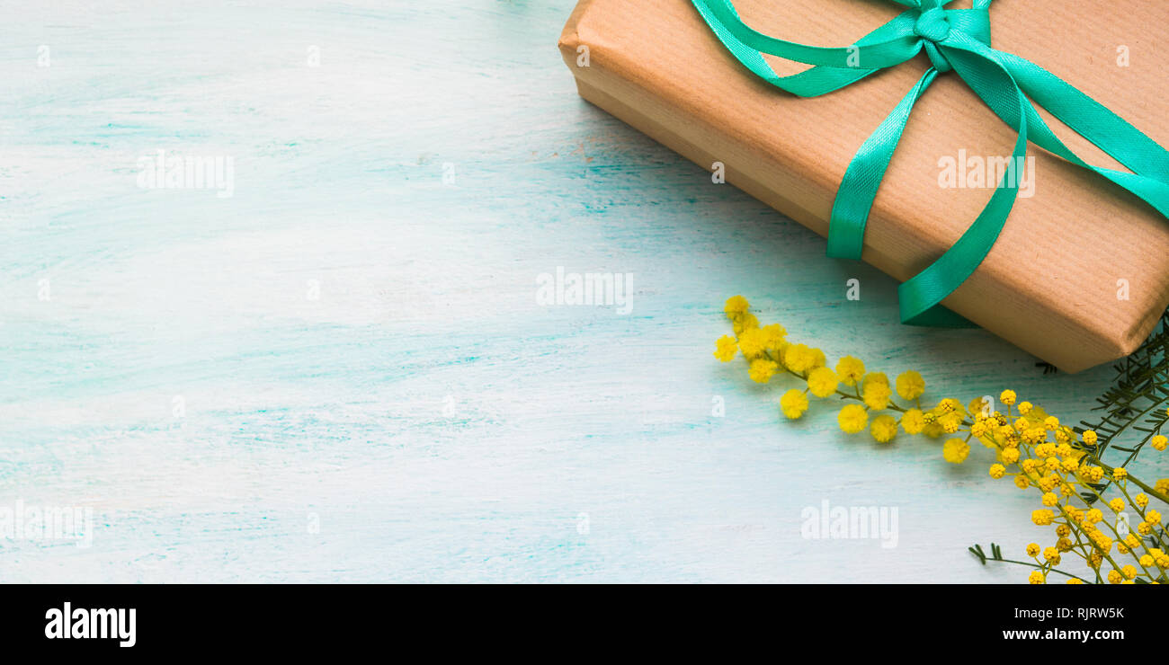 Mimosa and gift box with green ribbon. Woman's day symbol flat lay on