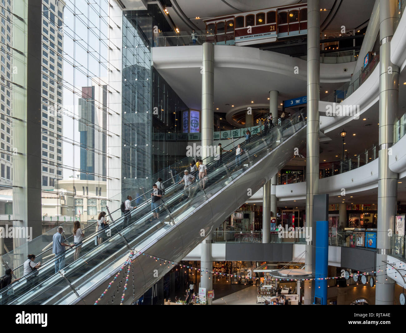 The interior of a modern shopping precinct in Bangkok Thailand with escalators and people shopping Stock Photo