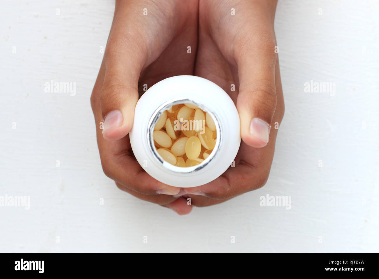 Hand holding bottle of vitamins against white background Stock Photo