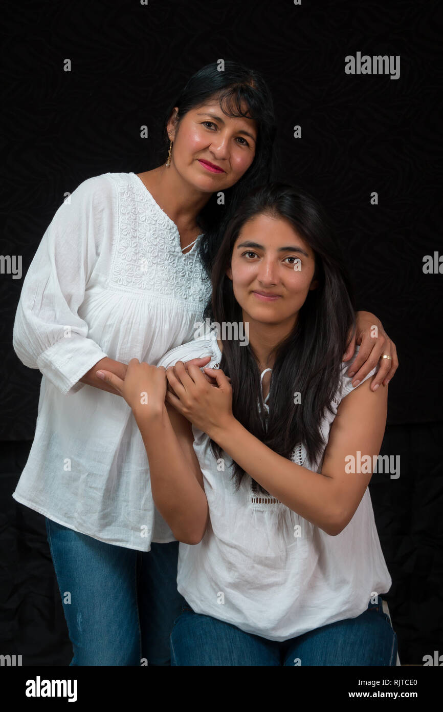 Mexican mother and daughter hugging on black background Stock Photo