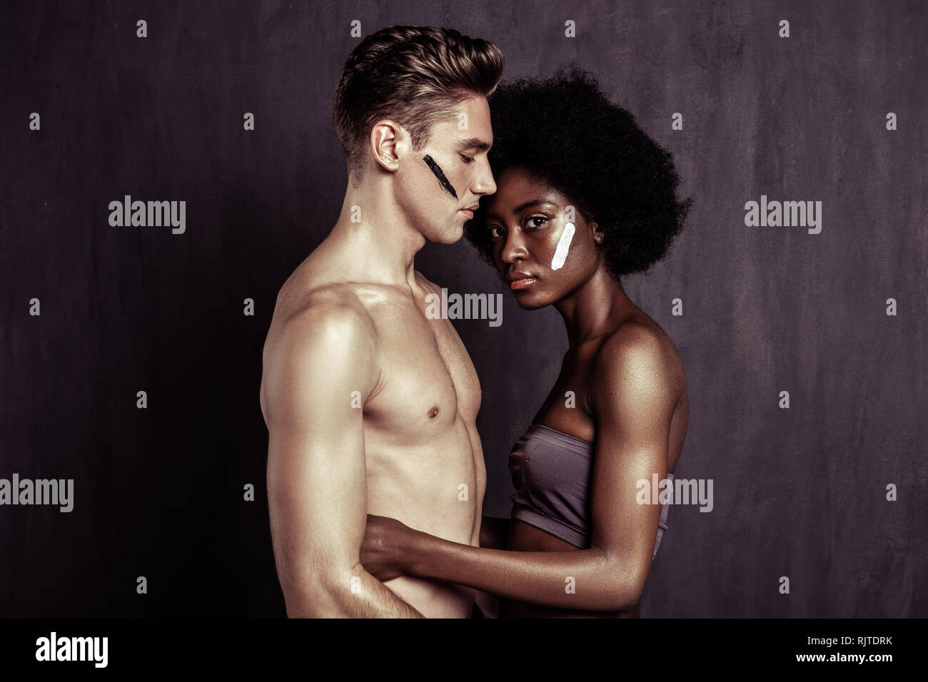 Nice pleasant couple standing against dark background Stock Photo