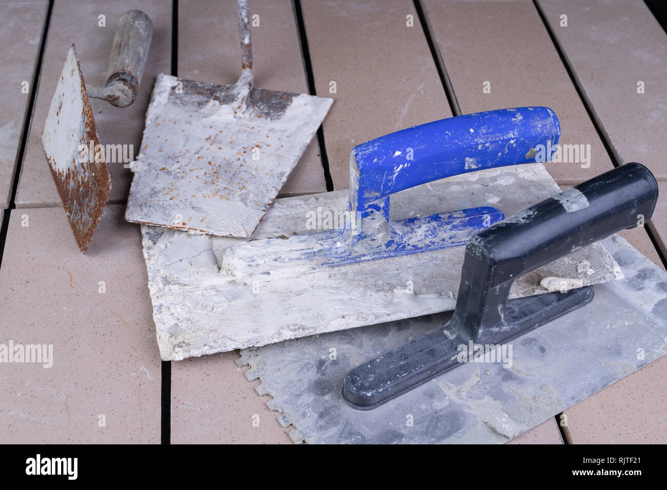 Tiles cut to size and trowels for applying mortar. Masonry accessories on a table. Dark
