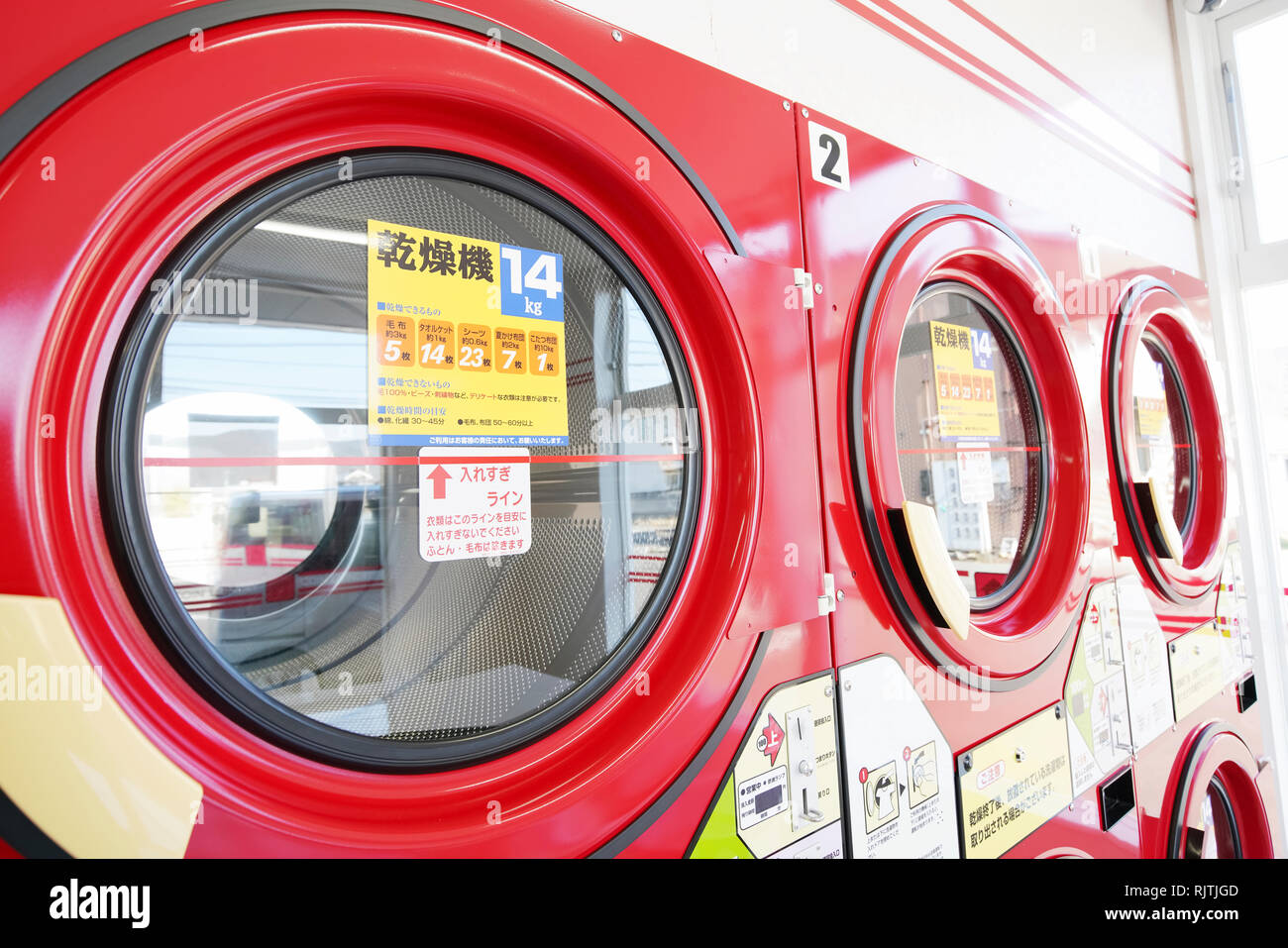 Row of industrial laundry machines in a public laundromat Stock Photo